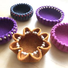 four felt bowls with beads on them sitting on a table