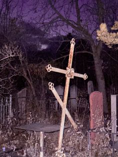 an old wooden cross sitting in the middle of a field next to a cemetery bench