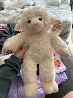 a white stuffed animal sitting on top of a pile of clothes next to a bed