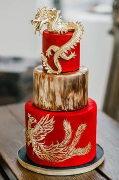 a three tiered red and gold wedding cake with a dragon decoration on the top