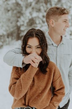 a man and woman are standing in the snow