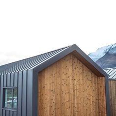 a house made out of metal and wood with mountains in the background