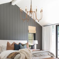 a large bed sitting under a chandelier in a bedroom next to a window