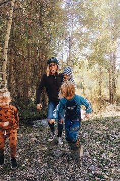 a woman and two children are walking through the woods