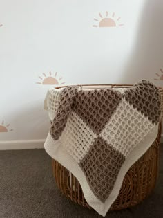 a brown and white blanket sitting on top of a wicker basket next to a wall