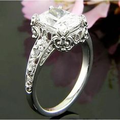 an engagement ring with a princess cut diamond in the center and filigrees on the sides