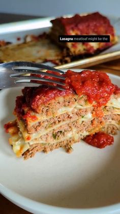 a white plate topped with lasagna covered in marinara sauce next to a fork