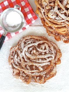 two pastries sitting on top of a table covered in powdered sugar