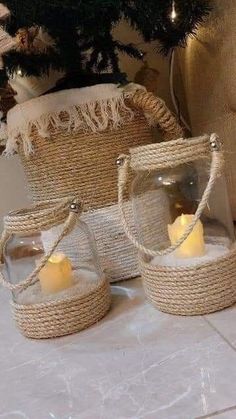 two glass jars with candles in them sitting on a table next to a christmas tree