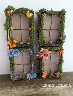 two old window frames are decorated with fake flowers and plants for the top one is made out of wire