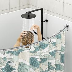 a shower curtain hanging from the side of a bath tub next to a white tiled wall