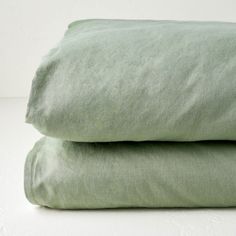 two sheets folded on top of each other in light green linens, one is plain and the other is plain