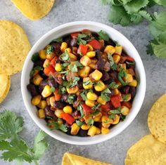 a white bowl filled with corn and black bean salsa next to tortilla chips