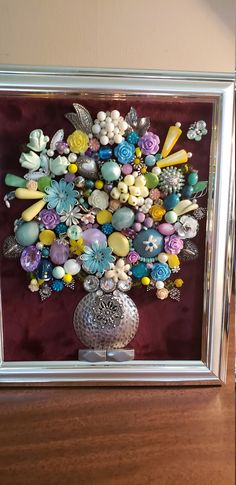 a silver vase filled with lots of different colored flowers on top of a wooden table