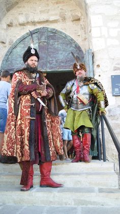 two men dressed in medieval costumes standing on steps