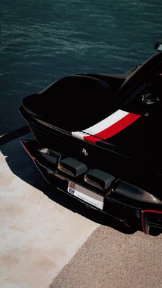 a black sports car parked next to the water