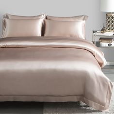 a bed with a pink comforter and two pillows on top of it in a bedroom