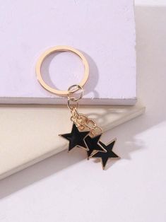 a gold keychain with two black stars hanging from it's side on a white surface