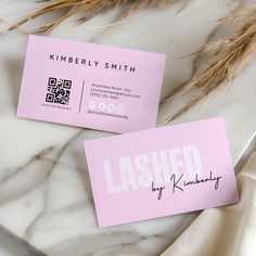 two business cards sitting on top of a marble table next to some dried grass and flowers