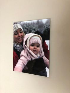 a woman holding a baby in her arms and smiling at the camera while wearing a knitted hat