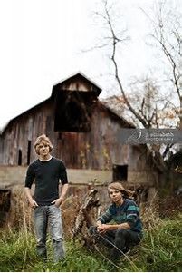 two people standing in front of a barn