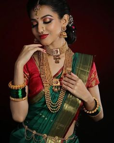 a woman in a green and red saree with gold jewelry on her neck, wearing a