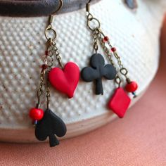 three hearts and two spades dangling from chains on a white vase with pink background