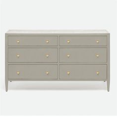 a grey dresser with gold handles and drawers