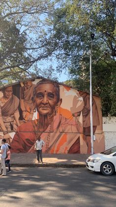 people standing in front of a large mural on the side of a building