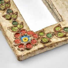 an old mirror is decorated with flowers and leaves