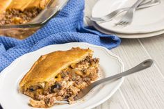 a white plate topped with a piece of pie next to a glass dish filled with meat