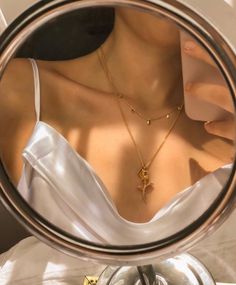 a woman's reflection in a mirror with a cross necklace on her neck,