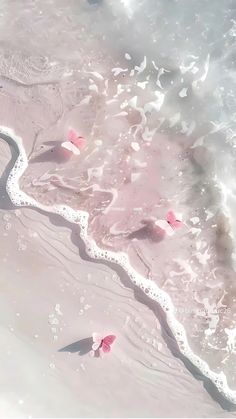 pink flowers are floating in the water at the edge of an ocean beach with waves