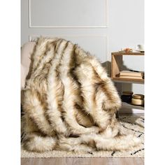 a bed with a fur blanket on top of it next to a chair and table