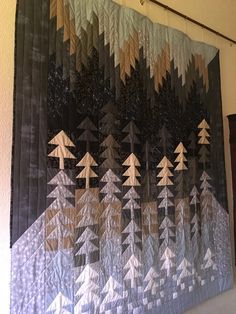 a quilt hanging on the wall with trees in it