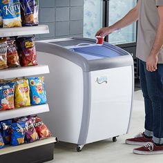 a man standing in front of a freezer filled with chips