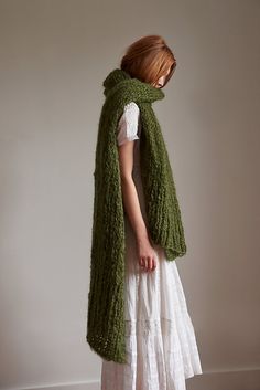 a woman in a white dress is wearing a green knitted scarf over her head