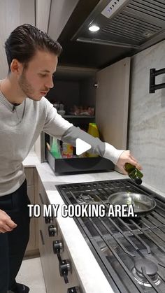 a man standing in front of an oven holding a bottle and looking at the stove