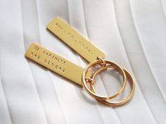 two personalized gold key chains on top of a white shirt