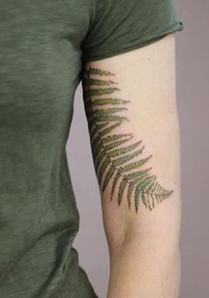 a woman's arm with a fern leaf tattoo on the left side of her arm