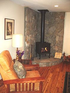 a living room filled with furniture and a wood burning stove in the middle of it