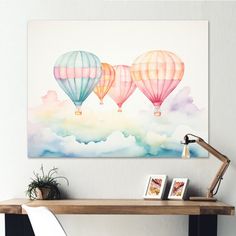 three hot air balloons floating in the sky above a wooden table with two pictures on it