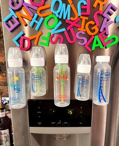 three water bottles sitting on top of a refrigerator freezer next to the word's alphabet