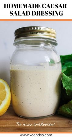 homemade caesar salad dressing in a mason jar next to lettuce and lemons