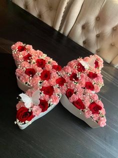 two heart shaped boxes with roses in them on a table