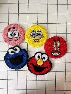 four sesame street characters are on a tile surface with white squares in the back ground