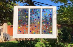 a window with several different colored glass balls on it in front of a tree and fence