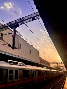 a train traveling down tracks next to a tall building