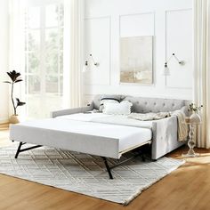 a bed sitting on top of a wooden floor next to a white wall in a living room