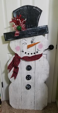 a snowman made out of wood with a hat and scarf on it's head